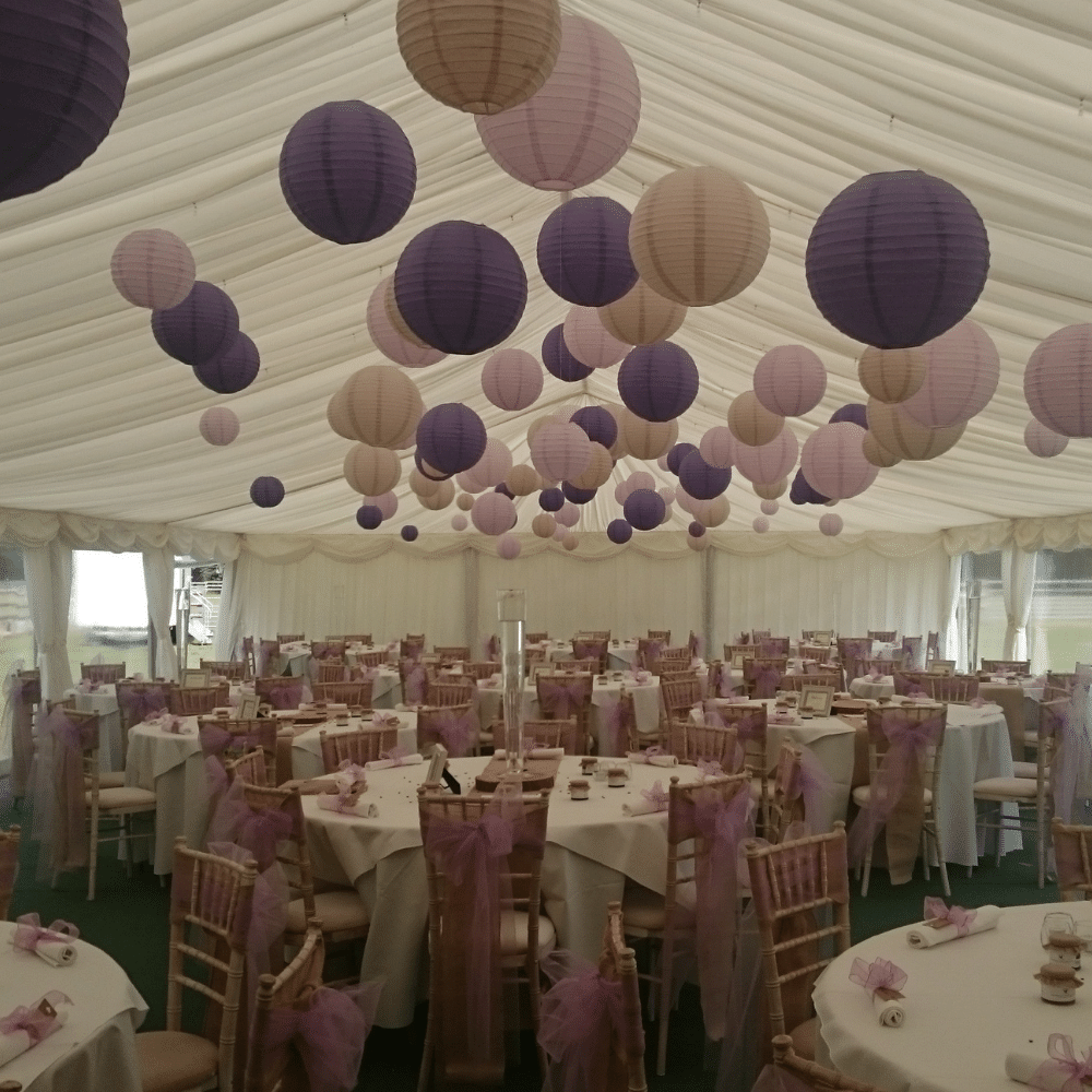 Paper lantern decorations above tables in a marquee
