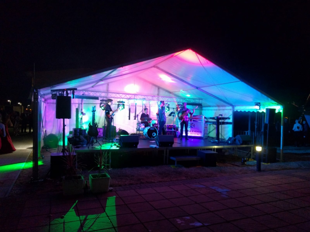 Band performing on a stage inside an event marquee