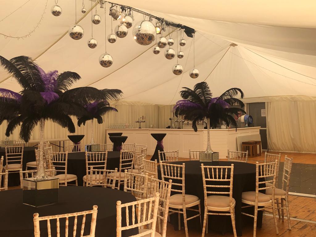 Marquee table setting with black linen and feather centrepieces